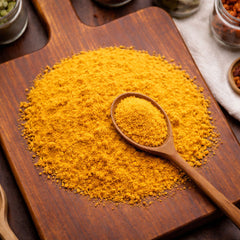 Fine, vibrant yellow bee pollen powder piled on a wooden surface.