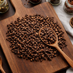 High-quality whole cloves displayed on a wooden board for culinary and aromatic use.