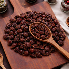 Whole dried red rosehips displayed on a wooden board for herbal tea and decoration.